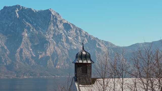 Aerial view of a snowy church steeple with Traunstein mountain, Austria