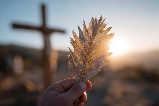 A hand holding a leaf near a cross.. Biblical scene