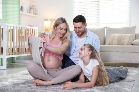 Pregnant woman with her daughter and husband on floor at home