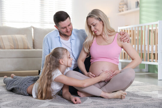 Pregnant woman with her daughter and husband on floor at home