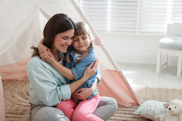 Mother and her daughter near toy wigwam at home, space for text © New Africa