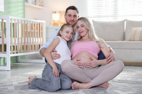 Pregnant woman with her daughter and husband on floor at home