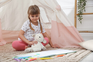 Little girl with toy sheep near wigwam at home © New Africa
