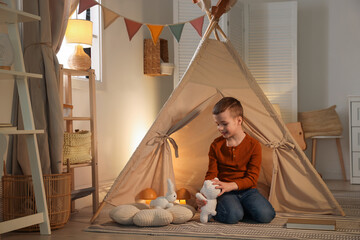 Little boy playing with toys near wigwam at home © New Africa
