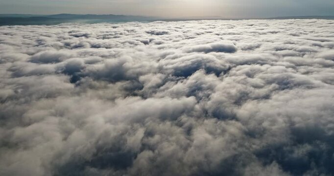 Aerial perspective above clouds sunset. Radiant sun rays blue sky horizon. Heavenly atmosphere white fluffy clouds golden hour sunlight. Cinematic nature background professional stock footage asset.
