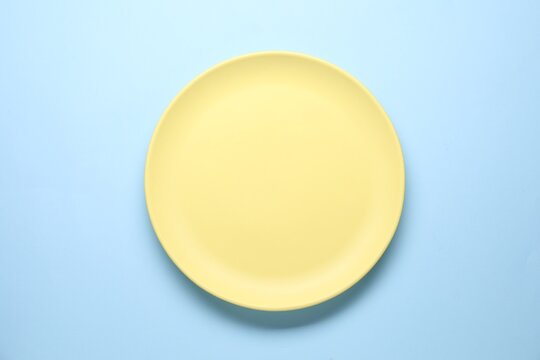 Empty plate on light blue background, top view