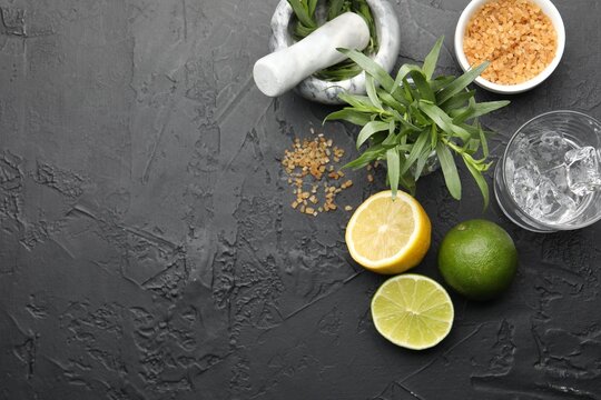 Mortar with pestle and ingredients for estragon lemonade on black table, flat lay. Space for text
