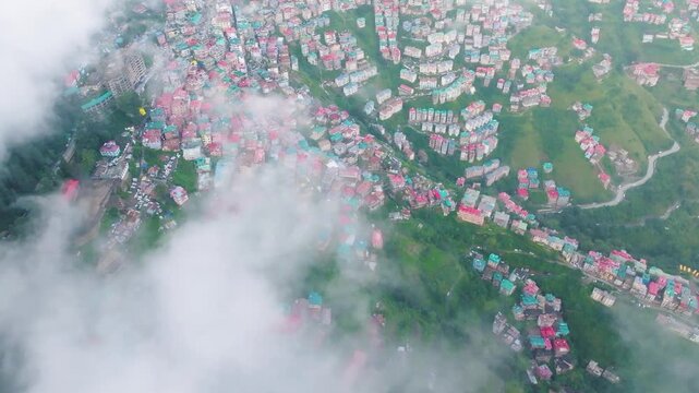 Cinematic Birds Eye drone Shot through low clouds revealing the densely packed mountain city of Shimla, India.
