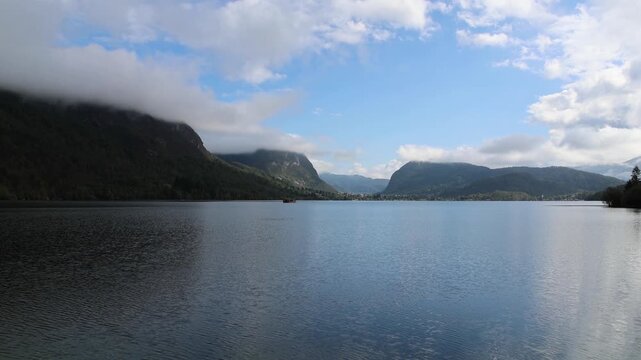lake bohinj with mountains background (aerial view of famous alpine travel destination in slovenia) boat kayaking scenic european tourism getaway (julian alps, europe) rain view scenic landscape