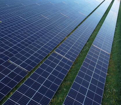 Solar energy center featuring long rows of photovoltaic panels arranged across a green open field. The installation highlights modern renewable‑energy production