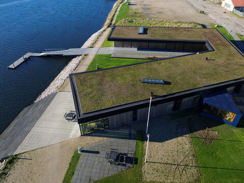 The distinct blue community clubhouse building positioned directly by the water at Haderslev Harbor