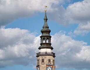 Victorian era clock tower adorned with ornate cornices and gilded weather vane against stormy skies © Vladimir