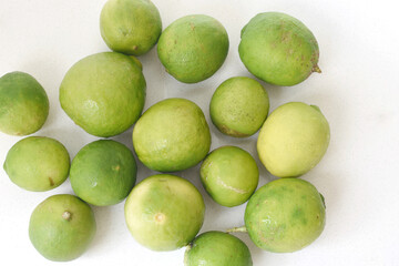 Fototapeta premium Top view of fresh green limes arranged on a clean white table, creating a bright and minimal citrus background. Ideal for concepts of freshness, healthy lifestyle, natural ingredients, summer drinks, 