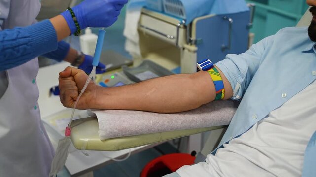 Nurse collecting blood from male donor during donation procedure