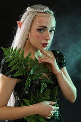 Naklejka premium Beautiful elf girl with floral decor on black background with smoke