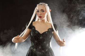Naklejka premium Beautiful girl dressed as elf on black background with smoke