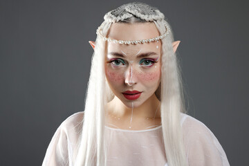 Naklejka premium Beautiful girl dressed as elf on grey background