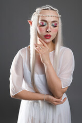 Naklejka premium Beautiful girl dressed as elf on grey background