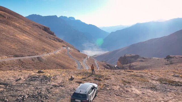 Drone orbiting a solitary traveler standing at a high-altitude mountain viewpoint in the Himalayas.