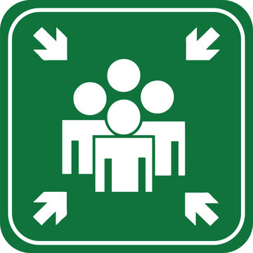 Green assembly point sign with white icons of people and arrows representing a safe meeting location for emergencies or evacuations