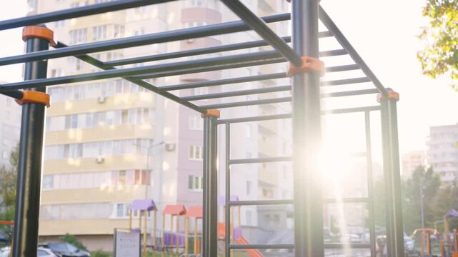Monkey bar frame stands above playground ground near housing blocks. Steel bars support climbing routes creating training station in yard