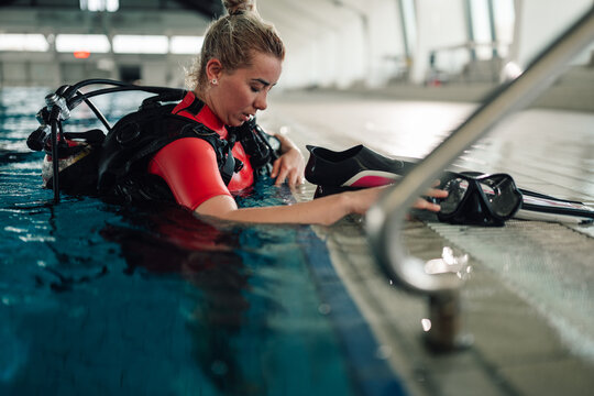 Woman preparing for scuba diving training in indoor pool, practicing water skills and underwater activity