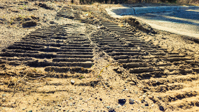 deep tracks left in the dirt, likely from heavy construction equipment like a bulldozer or excavator. development or leveling abstract background with copy space.