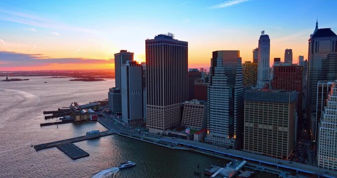 Setting sun seen behind the high-rises at the river waterfront. Drone footage over the waterscape in New York City, USA.