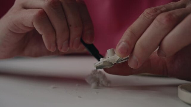 Maintenance of electric lint remover, hands use specialized brush to thoroughly clean collected fuzz, dust, and fibers from machine sharp cutting blades, close-up. Shooting in slow motion.