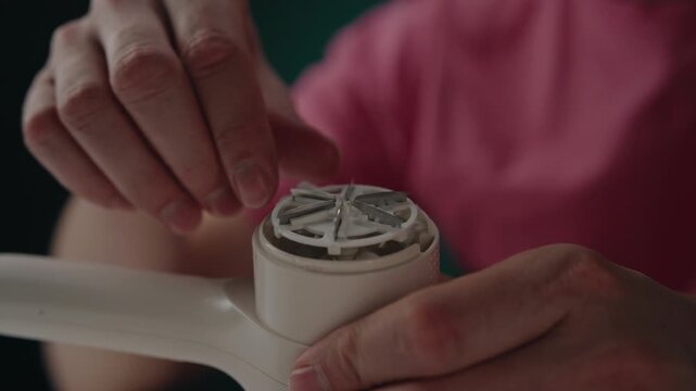 Man opening portable electric lint remover to clean dust collector, performing maintenance on device used for removing pills from clothes, close-up cropped shot. Shooting in slow motion.