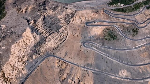 Top-down aerial aerial drone shot of the zigzagging Ka Loops mountain pass and highway in Himachal Pradesh, India.