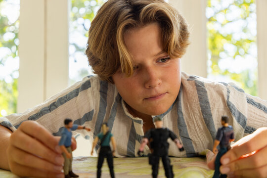 12 year old boy playing with toy soldiers at home