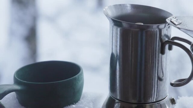 Watch as rich coffee brews slowly in a classic moka pot, filling the air with inviting aromas on a winter day.