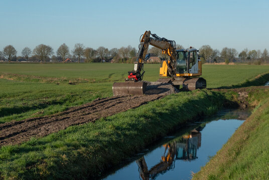 Excavator spreading dredge on field from cleaning a ditch