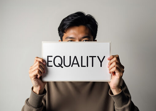 Asian man holding a white sign with the word EQUALITY written on it, advocating for social justice and human rights.