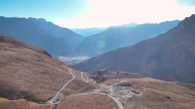 Epic drone view of a remote zigzag route traversing a steep, arid desert landscape in Spiti valley, Himachal, India.