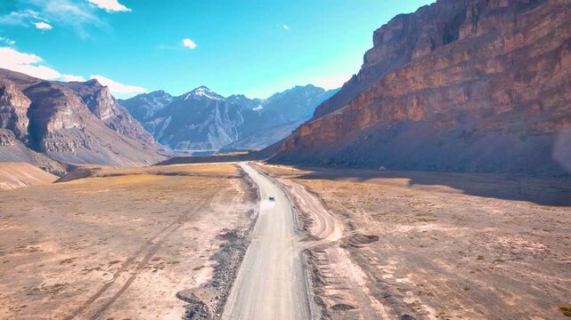 High altitude Cinematic drone tracking shot following a 4x4 SUV driving on a remote dirt road in spiti valley