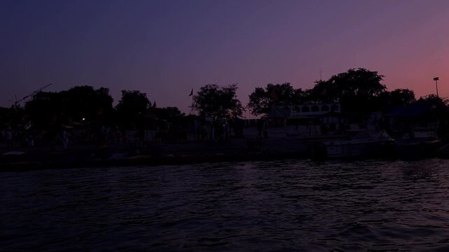 Calm Riverside at Twilight with Silhouetted Trees and Buildings, Peaceful Water Reflection, Scenic Sunset Landscape, Golden Hour Travel Background
