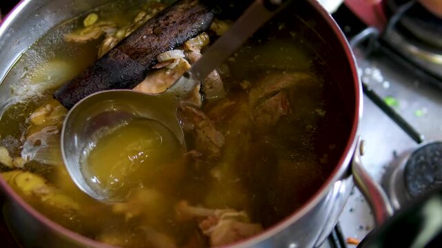 Vietnamese pho bo soup with various herbs, cinnamon, cinnamon stick, star anise, and onion. Cooking pot with bone broth meat pork and beef, aspic north food. spices on kitchen table. 