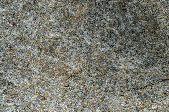Texture de roche granitique grise avec lichens et fissures naturelles