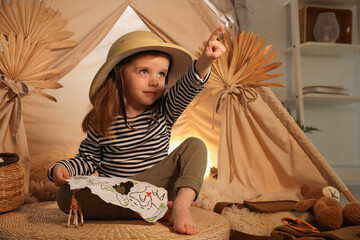 Little girl with drawing of map pointing at something near wigwam indoors © New Africa