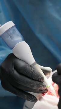 Close-up of dental air polishing tool in gloved hands during teeth cleaning. Professional plaque and stain removal in modern dental clinic. Oral hygiene and dentistry concept. Vertical video.