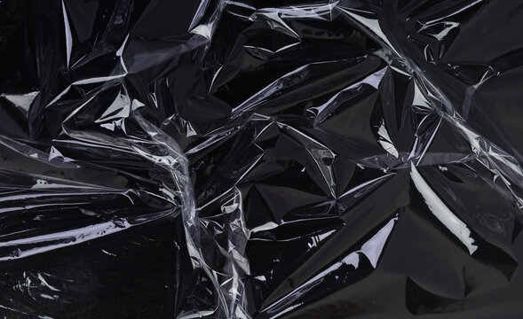 Wrinkled plastic wrap texture on a black background. Cellophane package wallpaper	
