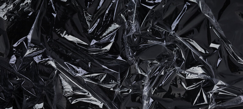 Wrinkled plastic wrap texture on a black background. Cellophane package wallpaper	
