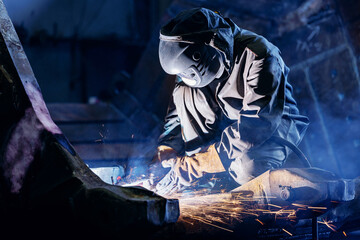 Welder grinding metal generating bright sparks in industrial shop, recovery work for excavator bucket © Parilov