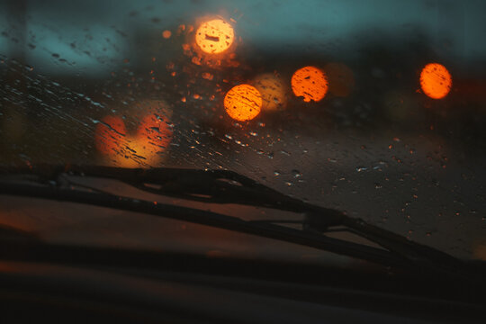 A rainy night drive through the city with blurred traffic lights ahead