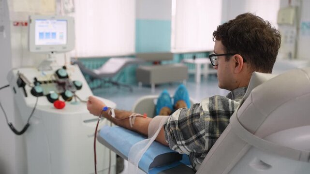 Male blood donor giving blood in hospital donation center