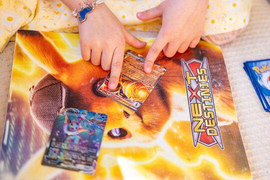 Young enthusiast Child playing with pokemon trading cards on album pikachu cover, Collecting cards, Childhood imagination and play, Battle friends, Fan Culture, Learning interaction, collectible hobby