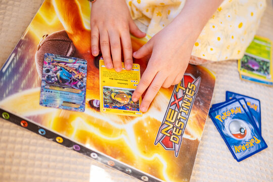 Young enthusiast Child playing with pokemon trading cards on album pikachu cover, Collecting cards, Childhood imagination and play, Battle friends, Fan Culture, Learning interaction, collectible hobby