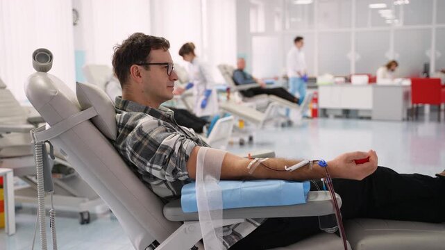 Male blood donor squeezing stress ball in hospital donation center